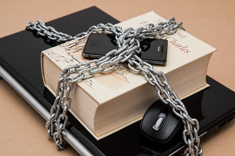 A laptop, book and a mobile phone covered in a chain.