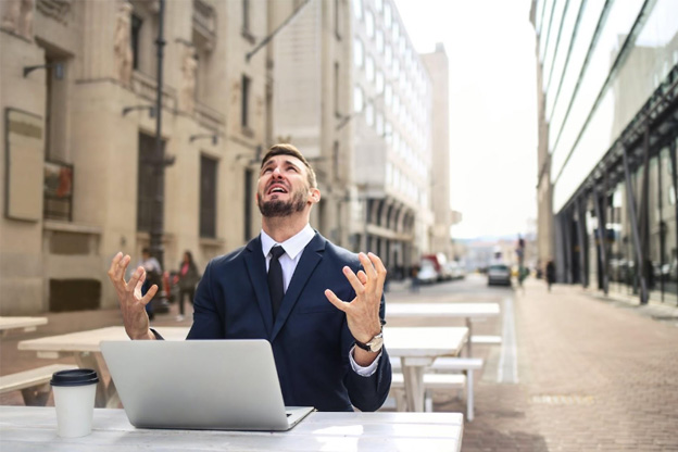 A person sitting with his laptop on a street facing IT Issues. 